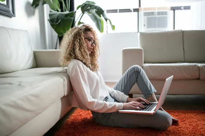 woman sitting at home using her laptop on the floor