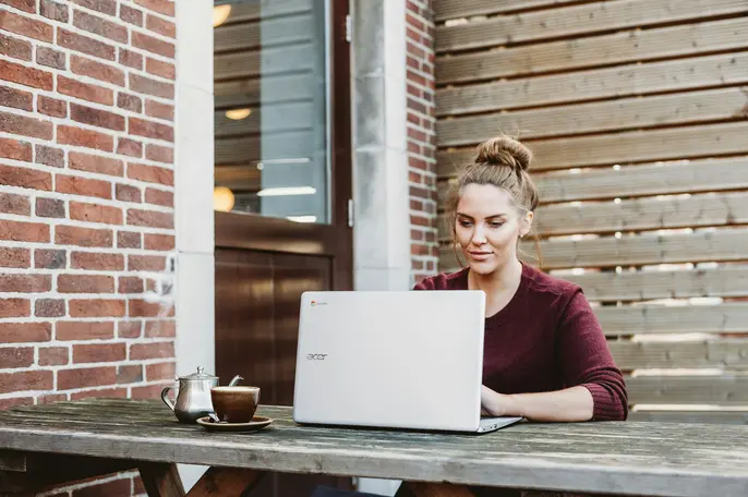 woman sitting outside on a porch using her laptop